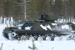 Blindé chenillé Patria TRACKX en camouflage hivernal dans une forêt enneigée