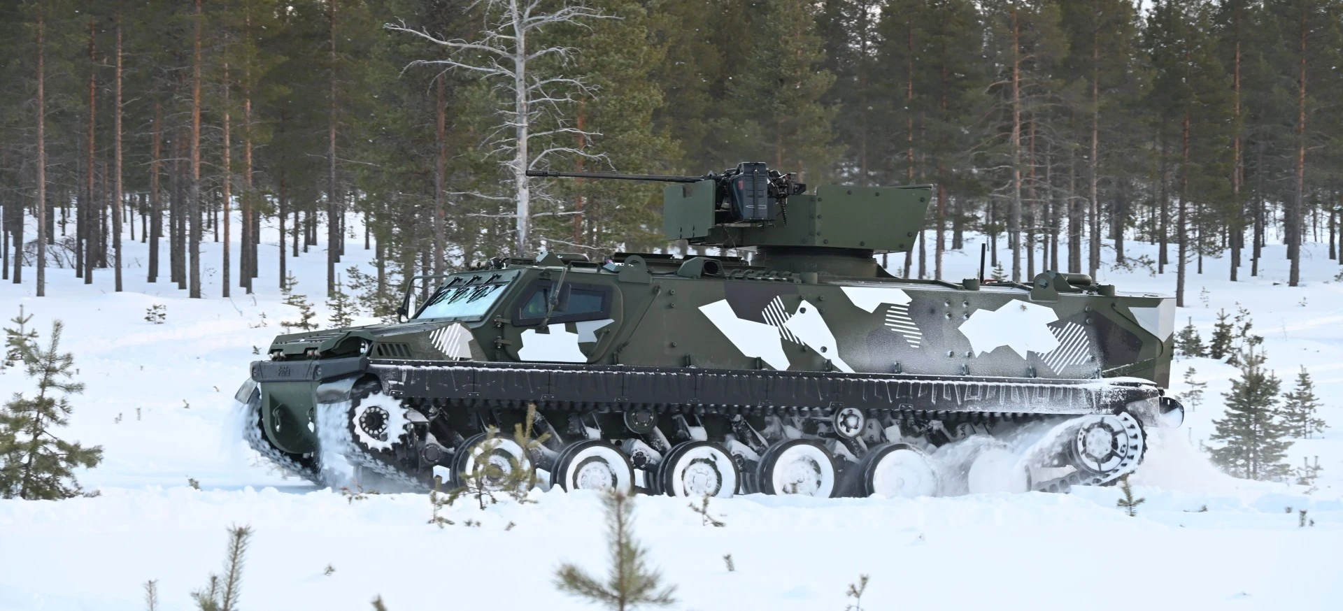 Blindé chenillé Patria TRACKX en camouflage hivernal dans une forêt enneigée